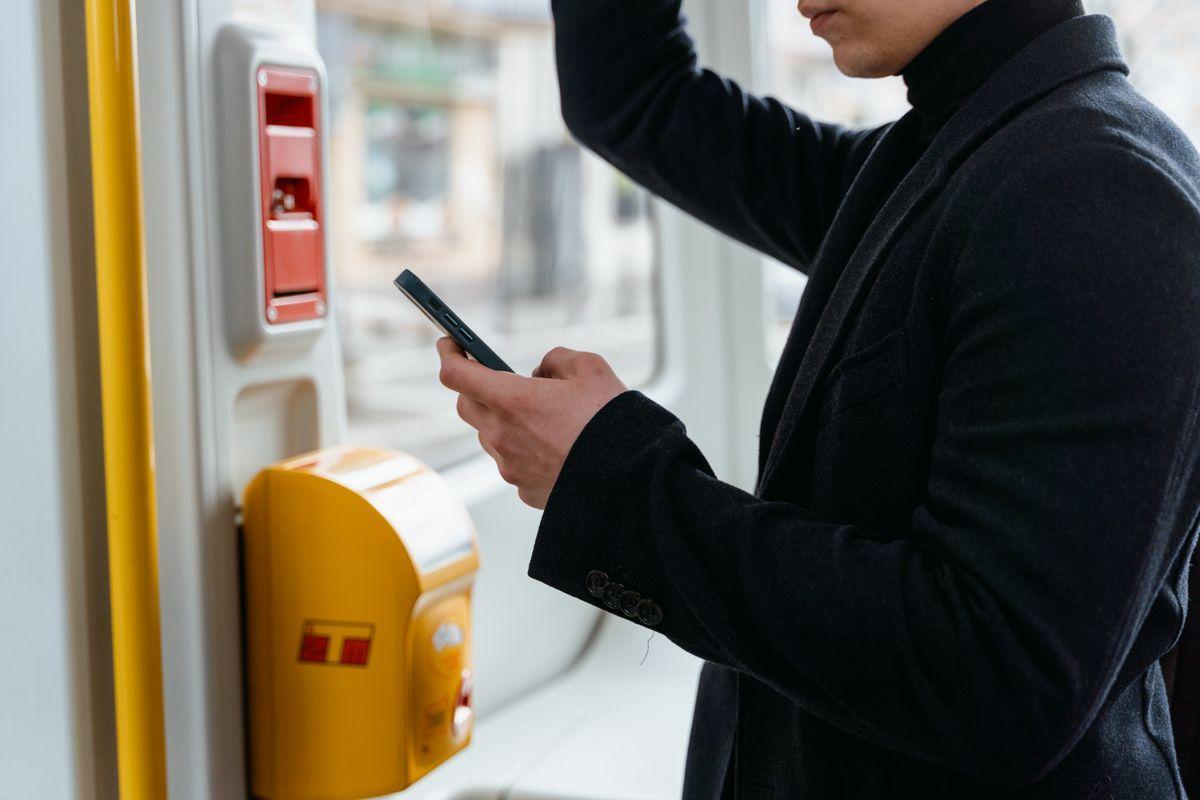 電車の中でスマートフォンを操作する人の手元